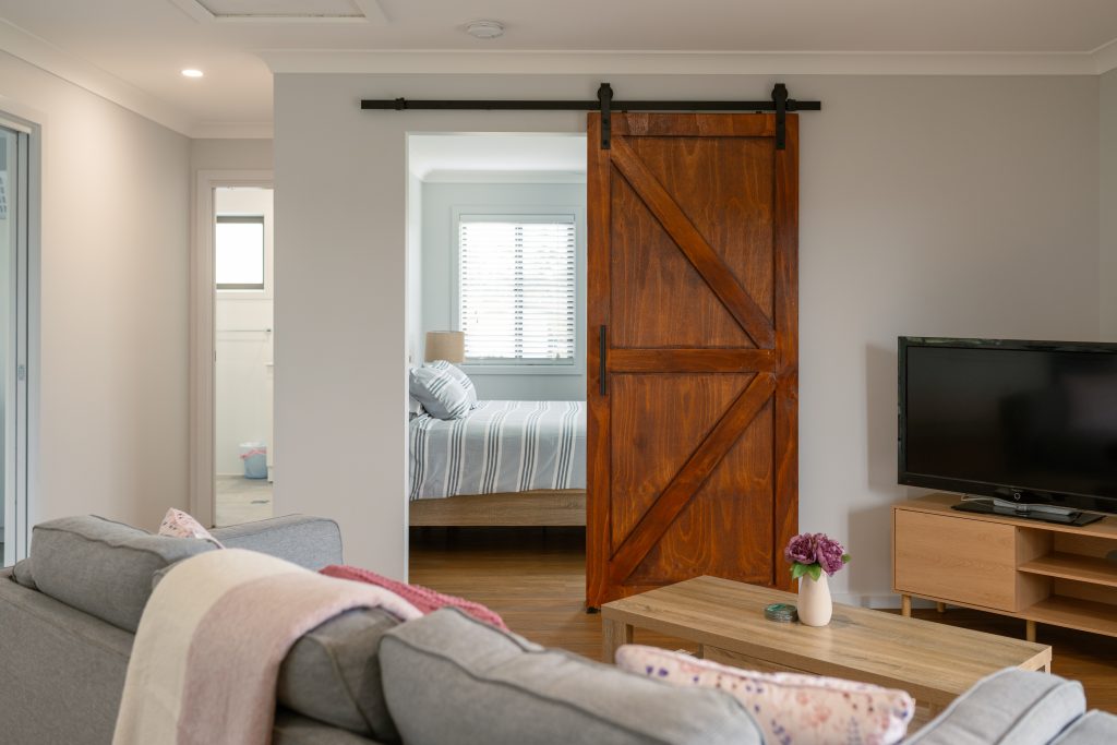 Cozy cabin interior featuring a wooden sliding barn door leading to a comfortable bedroom.